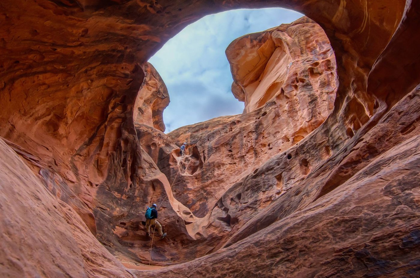 Canyoneers rappelling into a domed sandstone chamber on a High Spur / Robbers Roost descent